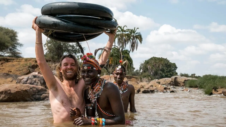 reiziger en samburu krijgers lachen samen in rivier in kenia met autobanden