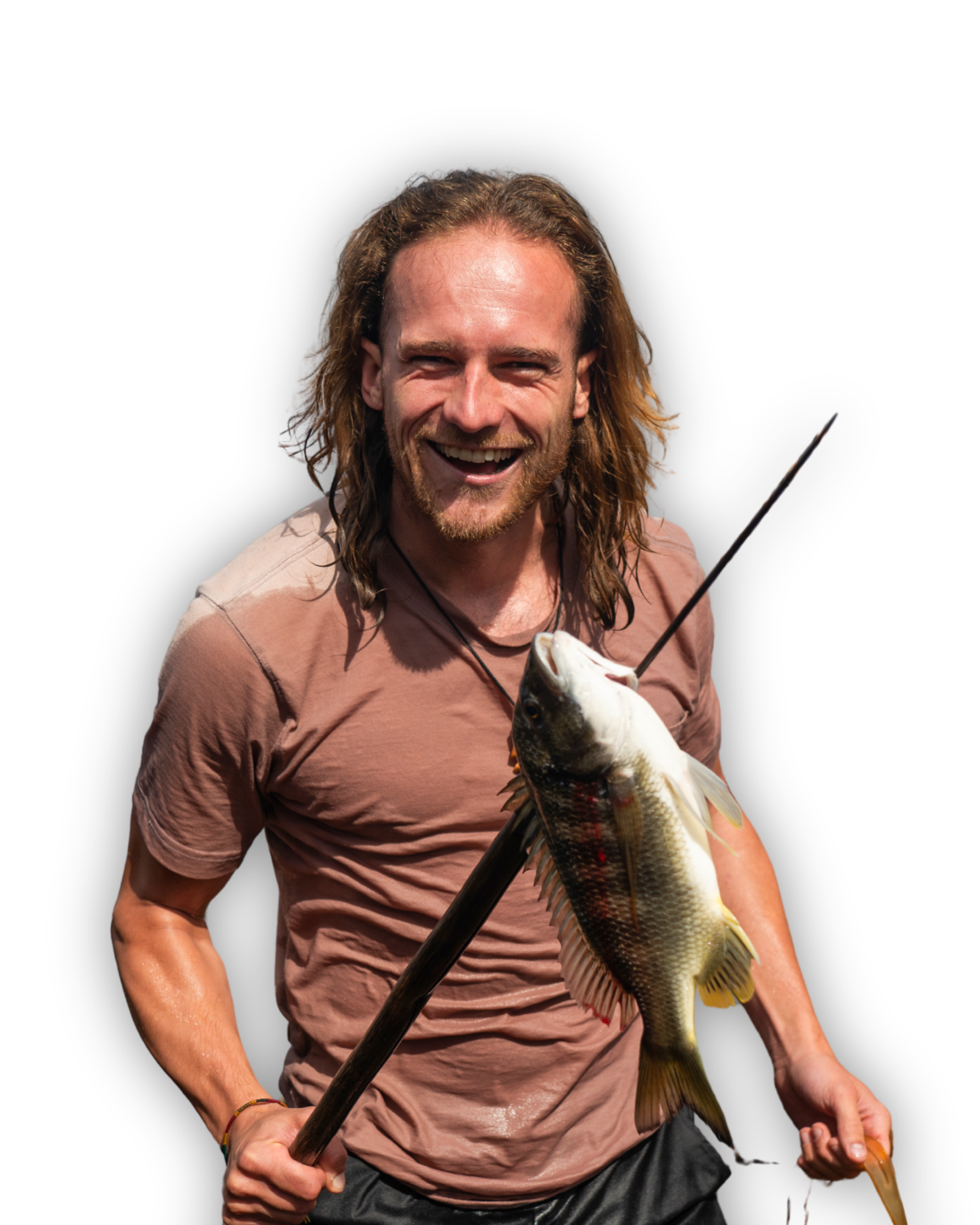 Een lachende man met lang haar houdt een grote vis aan een speer. Hij draagt een bruin t-shirt en staat tegen een effen witte achtergrond.