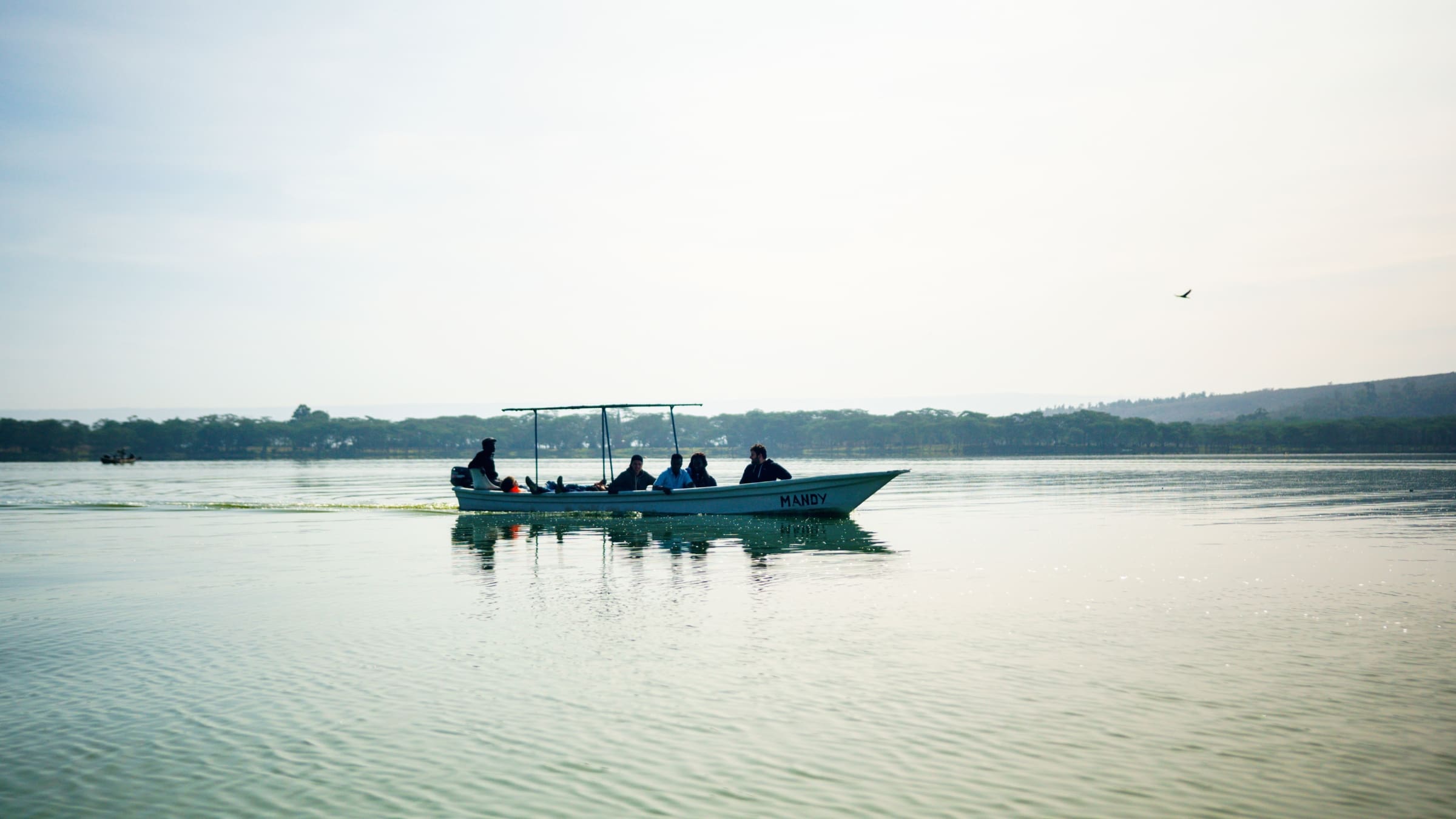 Kleine boot met toeristen vaart in de ochtend over Lake Naivasha met zacht licht en kalm water