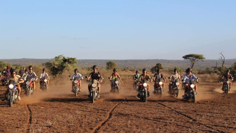 groep reizigers rijdt met motoren over stoffige savanne tijdens avontuurlijke tocht in kenia