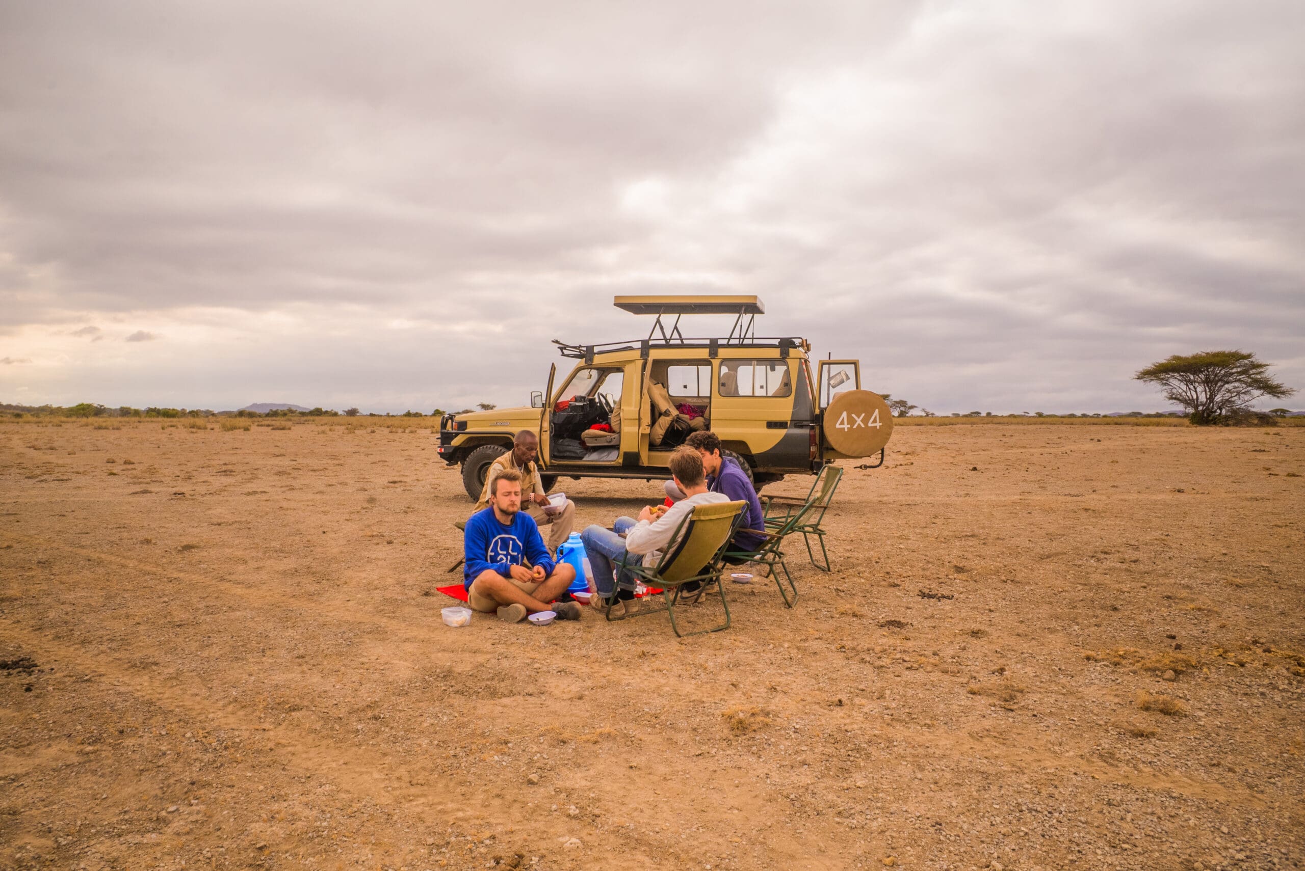 Reizigers genieten van picknick naast een safari jeep in de wildernis