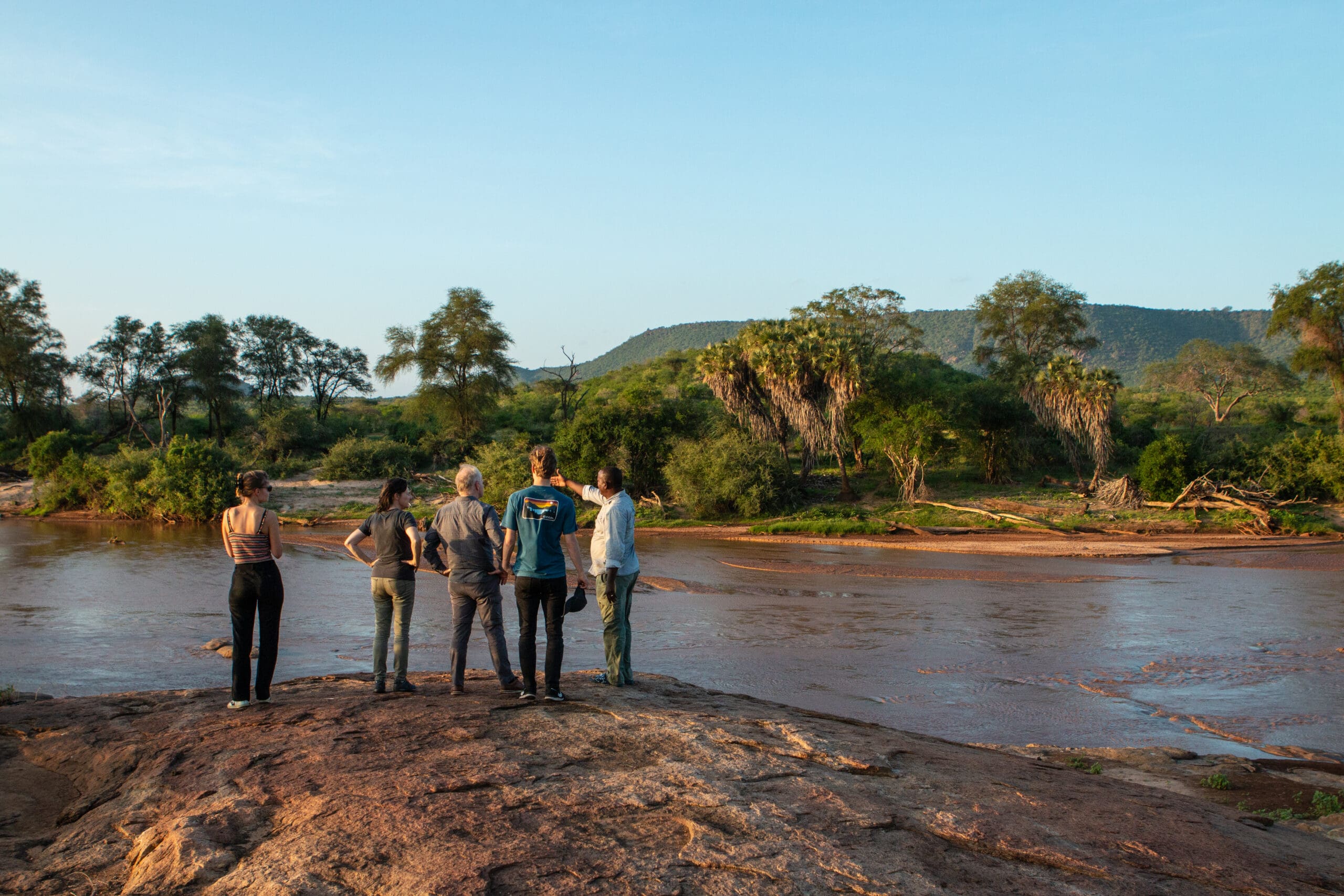 Reizigers kijken uit over de rivier en heuvels in Samburu