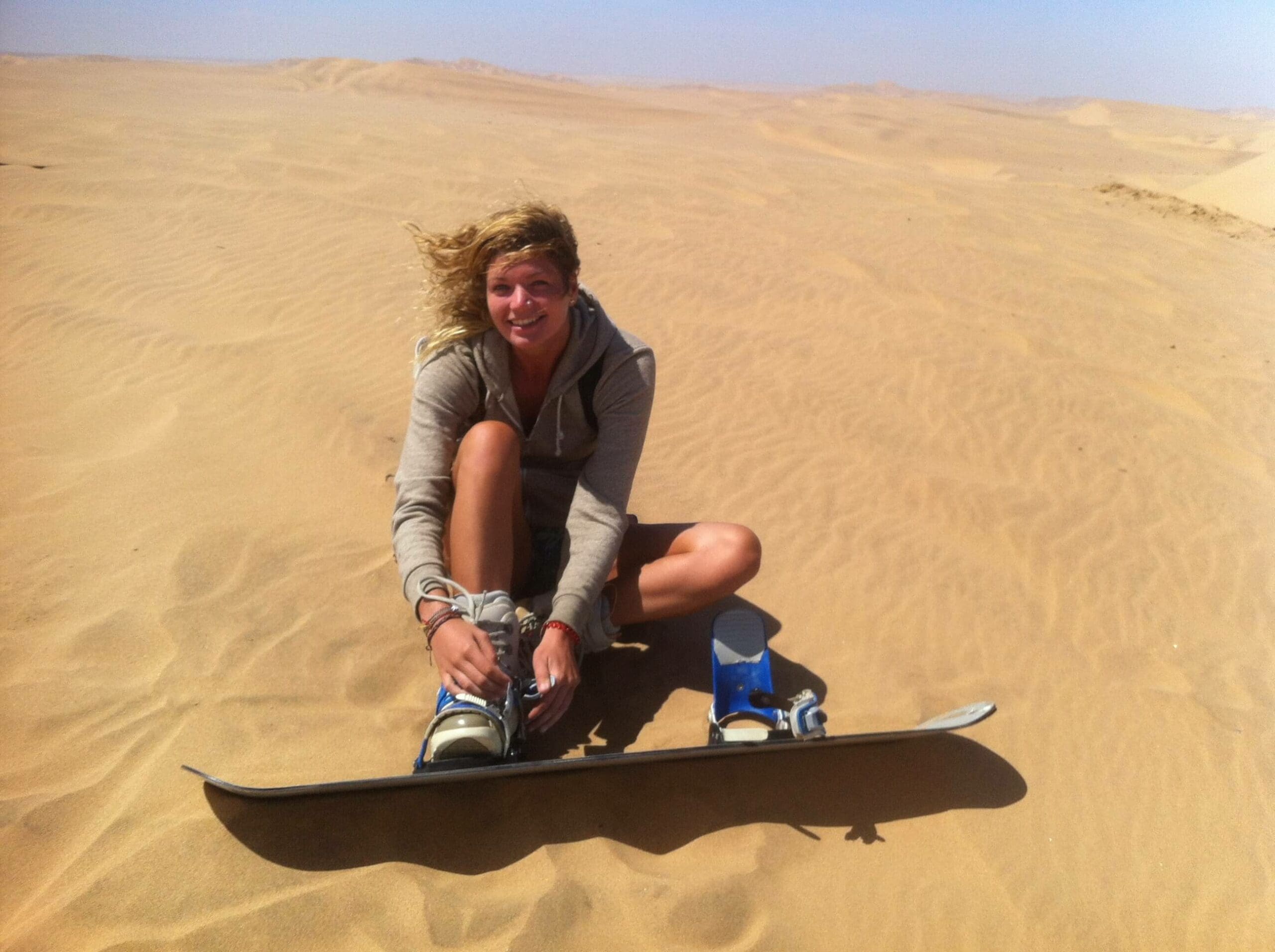 vrouw maakt zich klaar voor sandboarden in de woestijn van namibië