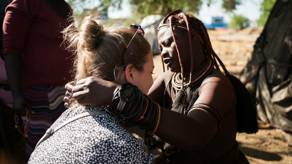 vrouw uit de himba stam begroet een reizigster tijdens een ontmoeting in noord namibië
