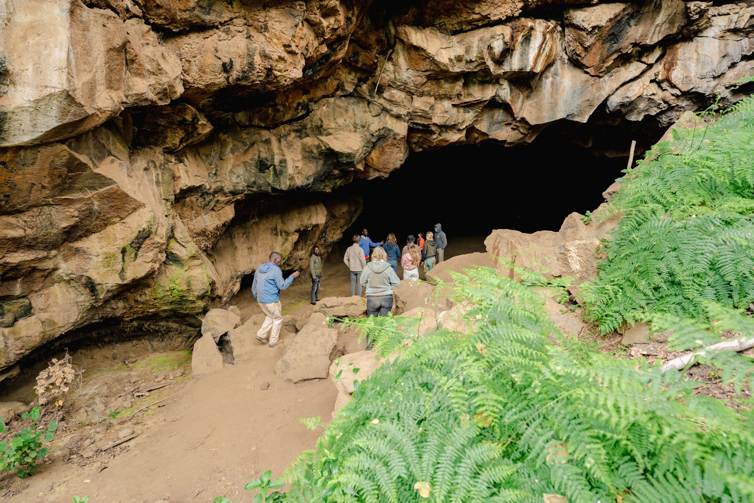 Groep mensen staat bij de ingang van een grote grot in Mount Suswa Kenia