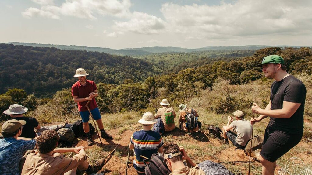groep wandelaars rust uit op heuvel met uitzicht over dichtbegroeid landschap in kenia