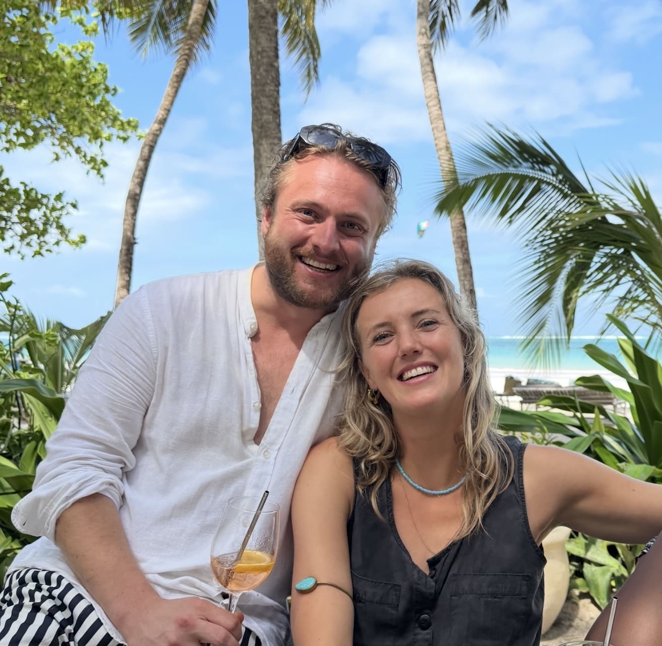 Een glimlachende man en vrouw poseren samen in een resort aan het strand.